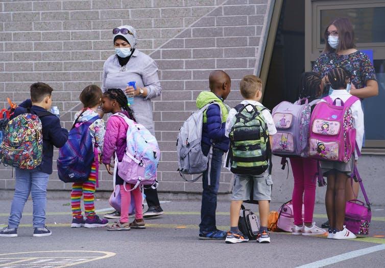 Teachers greet students in the school yard at the Philippe-Labarre Elementary School in Montréal, Aug. 27, 2020. 