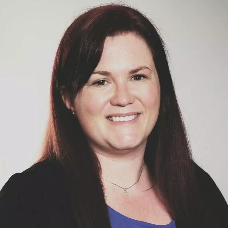 A woman with brown hair smiles at the camera