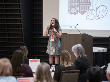 Mona stands on stage pitching