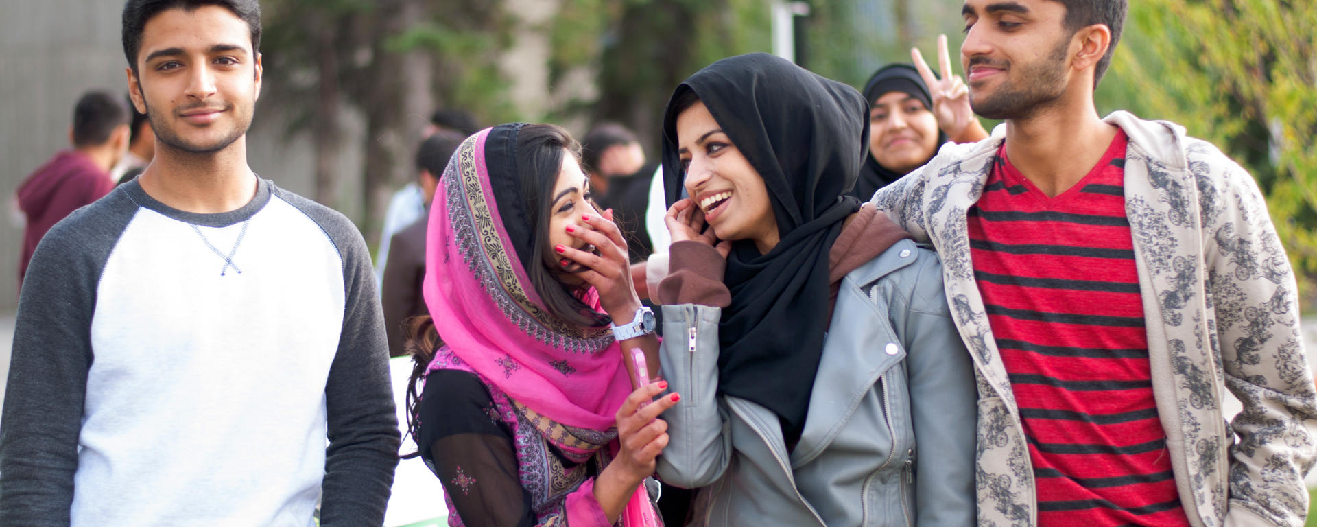 A group of students laughing and talking with one another on campus