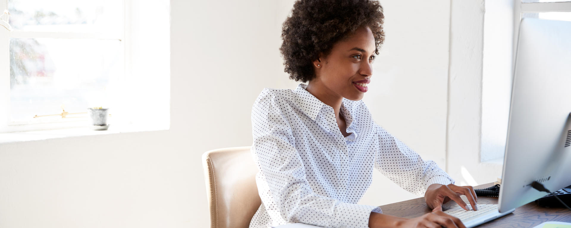 Black female sitting at a desk working on a computer