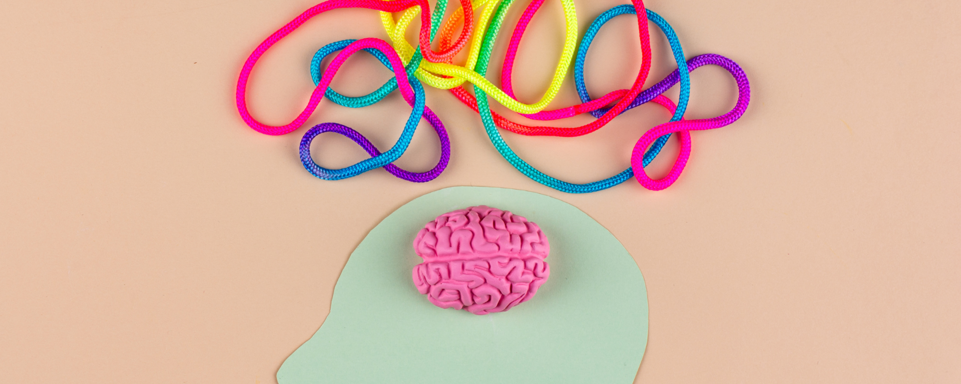 A felt image of a person's head sits below a colourful assortment of yarn depicting their many thoughts