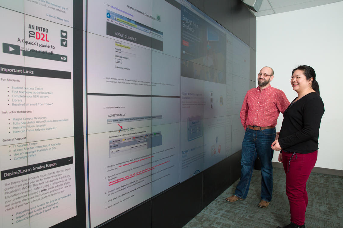 D'Arcy Norman and Leanne Wu standing in front of a wall of screens