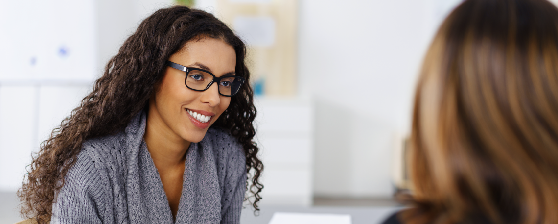 Woman with glasses smiling at woman across from her