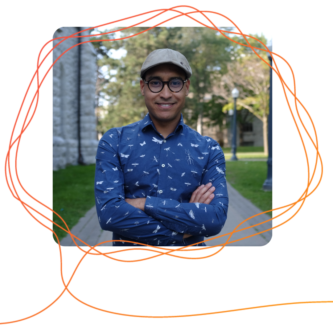 Alan Martino, a brown man in a cap standing outside with his arms crossed.