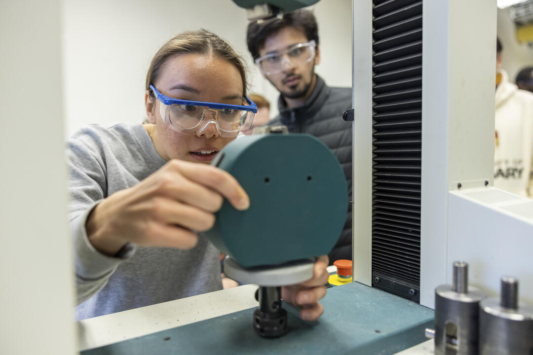 A student in the Schulich School of Engineering examines a machine while wearing protective eyewear.