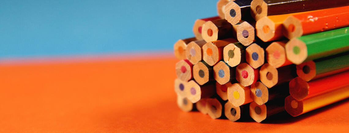 Stacked pencils on an orange surface