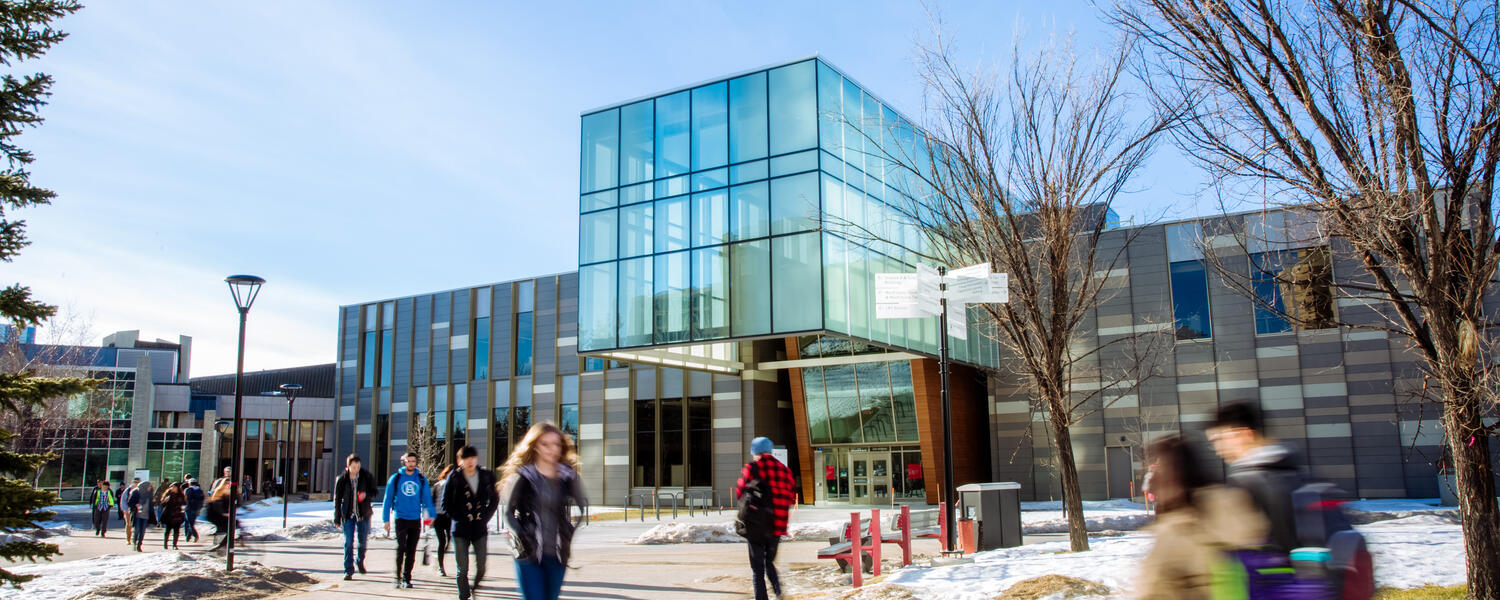 People walking past the Taylor Institute building on a sunny day.