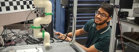 A male student operates engineering equipment on a lab table