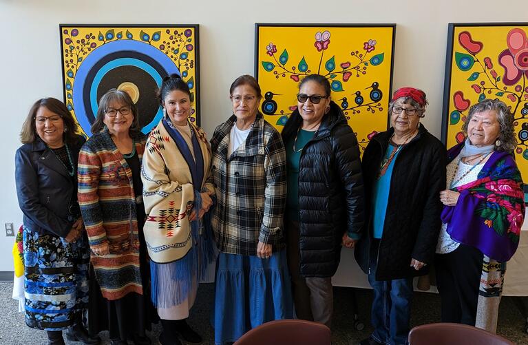 Jennifer Leason and her community in front of paintings she made