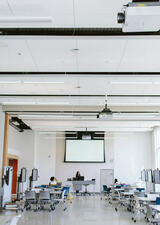 Photo of a classroom with student and teacher talking to oneanother