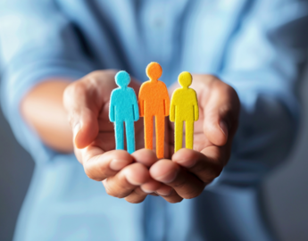 A pair of hands hold differently coloured felt statues of people